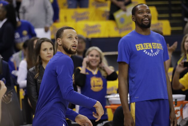 Golden State Warriors' Stephen Curry, left, watches his shot next to teammate Kevin Durant as players warm up for Game 1 of an NBA basketball second-round playoff series against the New Orleans Pelicans,Saturday, April 28, 2018, in Oakland, Calif. (AP Photo/Marcio Jose Sanchez)