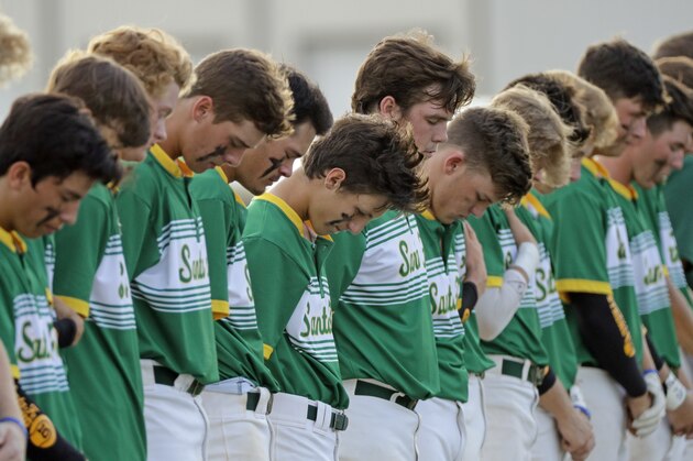Santa Fe High School baseball players bow their heads in a moment of silence for the shooting victims at their school before a baseball game against Kingwood Park High School in Deer Park, Texas, Saturday, May 19, 2018. A gunman opened fire inside Santa Fe High School Friday, May 18, 2018, killing at least 10 people. (AP Photo/David J. Phillip)