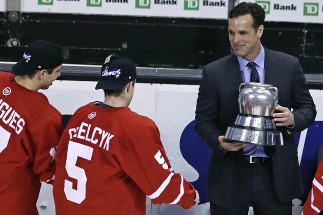 FILE - In this Feb. 23, 2015, file photo Boston University hockey head coach David Quinn, right, hands the Beanpot trophy to Matt Grzelcyk (5) and Evan Rodrigues, left, after their overtime win against Northeastern in Boston. NHL teams are thinking outside the box to find coaches. Quinn has been linked to the Rangers but will stay at least one more year and run the U.S. world junior team like Housley before likely being the next to graduate from college to the NHL. (AP Photo/Charles Krupa, file)