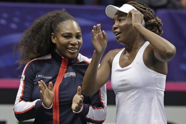 USA's Venus Williams, right, and Serena Williams, left, celebrate after defeating Netherlands in the first round of Fed Cup tennis competition in Asheville, N.C., Sunday, Feb. 11, 2018. (AP Photo/Chuck Burton)