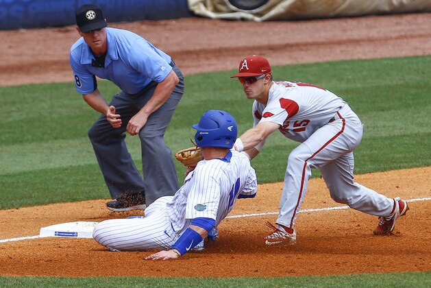 Florida's Jonah Girand (11) is tagged out by Arkansas third baseman Casey Martin (15) as he tries to slide into third base during the third inning of a Southeastern Conference tournament NCAA college baseball game, Friday, May 25, 2018, in Hoover, Ala. (AP Photo/Butch Dill)