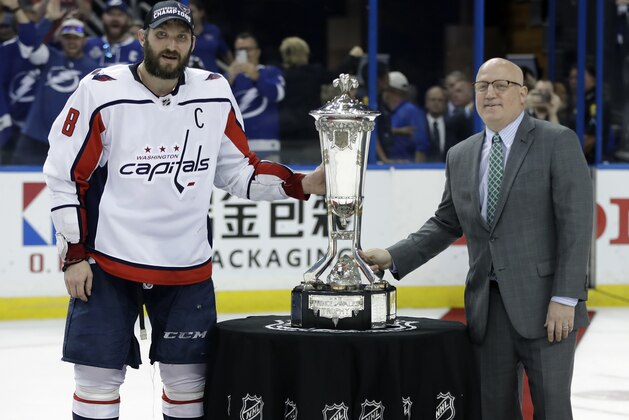 Washington Capitals left wing Alex Ovechkin, left, poses with NHL Deputy Commissioner Bill Daly and the Prince of Wales trophy after the Capitals defeated the Tampa Bay Lightning 4-0 during Game 7 of the NHL Eastern Conference finals hockey playoff series Wednesday, May 23, 2018, in Tampa, Fla. (AP Photo/Chris O'Meara)