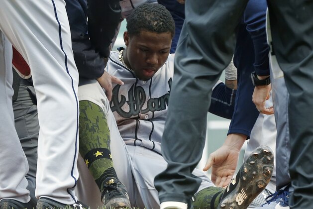 Team personnel help Atlanta Braves' Ronald Acuna Jr. after he was injured while running out a single during the seventh inning of an interleague baseball game against the Boston Red Sox, Sunday, May 27, 2018, in Boston. (AP Photo/Michael Dwyer)