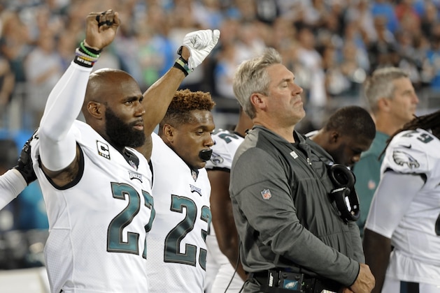 Philadelphia Eagles players Malcolm Jenkins (27) and Rodney McLeod (23) raise their fists as they stand with head coach Doug Pederson during the national anthem before an NFL football game against the Carolina Panthers in Charlotte, N.C., Thursday, Oct. 12, 2017. (AP Photo/Mike McCarn)