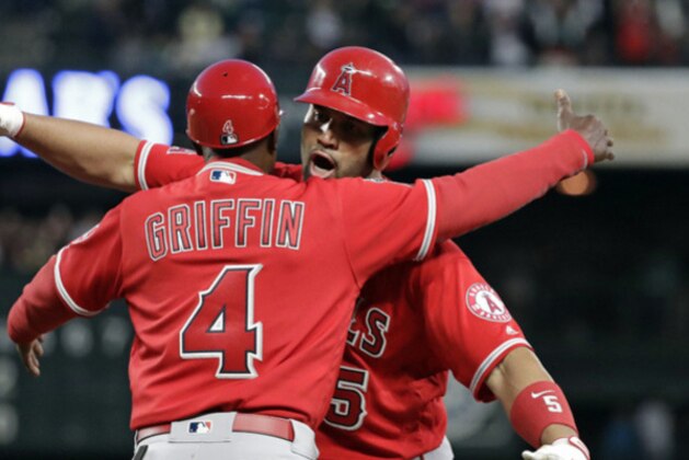 Los Angeles Angels' Albert Pujols, right, embraces first base coach Alfredo Griffin after hitting a single against the Seattle Mariners in the fifth inning of a baseball game Friday, May 4, 2018, in Seattle. The hit is the 3,000th of Pujols' career. (AP Photo/Elaine Thompson)