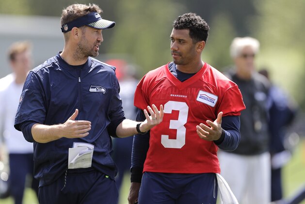 Seattle Seahawks quarterback Russell Wilson, right, talks with offensive coordinator Brian Schottenheimer, left, following NFL football practice, Wednesday, May 30, 2018, in Renton, Wash. (AP Photo/Ted S. Warren)