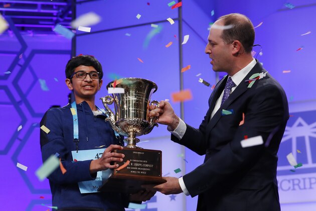 Karthik Nemmani, 14, from McKinney, Texas, left, holds his trophy with President and CEO of the E.W. Scripps Company Adam Symson as confetti falls after winning the Scripps National Spelling Bee in Oxon Hill, Md., Thursday, May 31, 2018.  (AP Photo/Jacquelyn Martin)