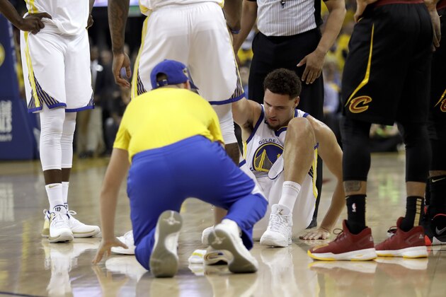 Golden State Warriors guard Klay Thompson is helped off the floor during the first half of Game 1 of basketball's NBA Finals between the Warriors and the Cleveland Cavaliers in Oakland, Calif., Thursday, May 31, 2018. (AP Photo/Marcio Jose Sanchez)