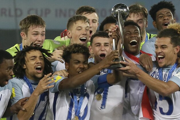 FILE - This is a Saturday, Oct. 28, 2017 file photo of England's soccer team as they celebrate with the trophy after winning the FIFA U-17 World Cup in Kolkata, India. England might to the first and last team to be holders of both the Under-20 and Under-17 World Cups. FIFA is looking to merge the youth tournaments won last year by England to create a 48-team competition, emulating the expansion of the main men’s World Cup. Officials are exploring the merits of an age cut-off at 18 or 19. (AP Photo/Anupam Nath/File)