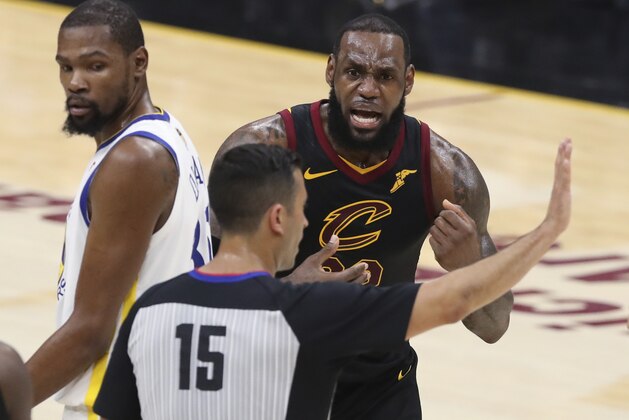 Cleveland Cavaliers' LeBron James argues a call with referee Zach Zarba (15) during the first half against the Golden State Warriors in Game 3 of basketball's NBA Finals, Wednesday, June 6, 2018, in Cleveland. Warriors' Kevin Durant is at left. (AP Photo/Carlos Osorio)