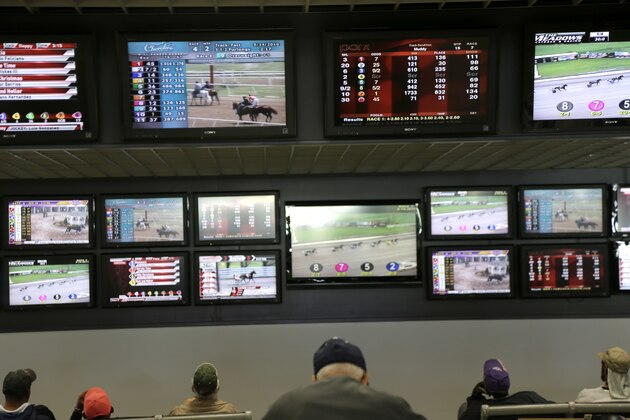 Men watch horse racing on an array of screen at Monmouth Park Racetrack in Oceanport, N.J., Monday, May 14, 2018. The Supreme Court on Monday gave its go-ahead for states to allow gambling on sports across the nation, striking down a federal law that barred betting on football, basketball, baseball and other sports in most states. (AP Photo/Seth Wenig)