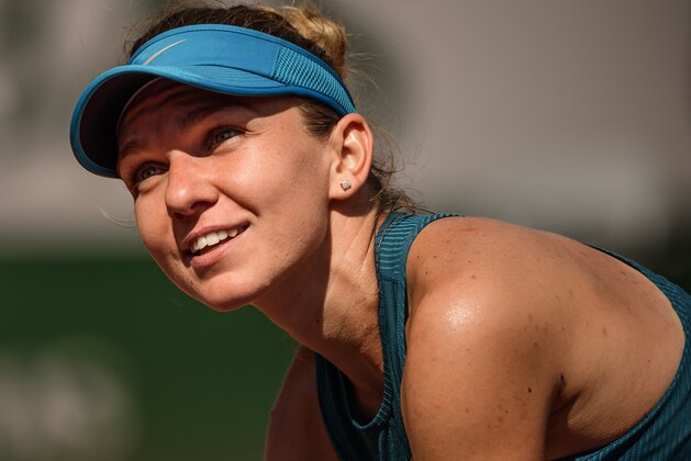 PARIS, FRANCE - JUNE 07: Simona Halep of Romania looks up at Fabrice Santoro who is conducting the post match interview after her victory over Garbine Muguruza of Spain 6-1 6-4 in the semi finals of the women's singles at Roland Garros during the French Open on June 7, 2018 in Paris, France. (Photo by Mike Frey/Getty Images)