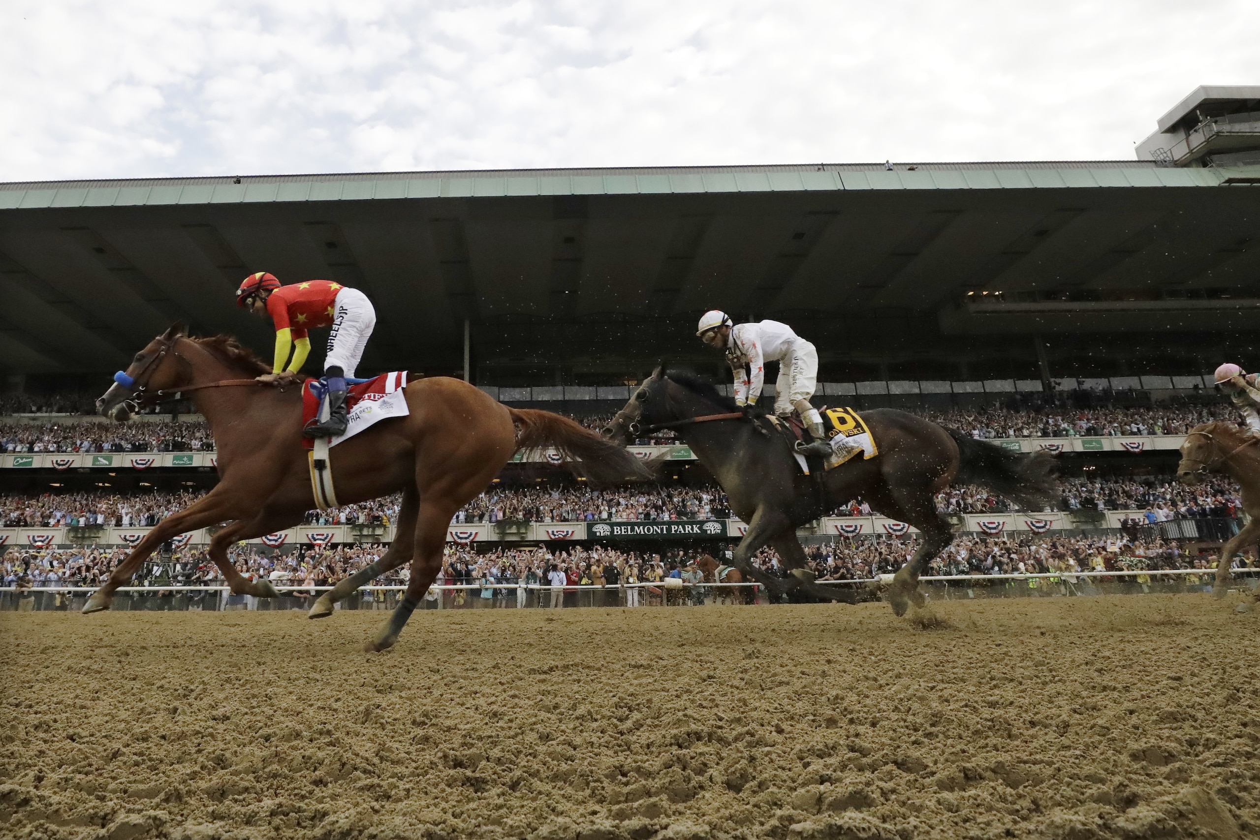 Justify, left, with jockey Mike Smith up, crosses the finish line to win the 150th running of the Belmont Stakes horse race and the Triple Crown, Saturday, June 9, 2018, in Elmont, N.Y. Gronkowski (6), with Jose Ortiz up, was second. (AP Photo/Julio Cortez)
