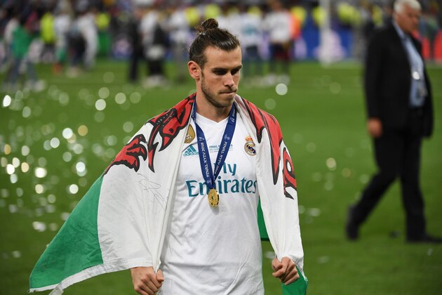 Real Madrid's Welsh forward Gareth Bale with his winner's medal and a Welsh flag on the pitch as Real Madrid players celebrate winning the UEFA Champions League final football match between Liverpool and Real Madrid at the Olympic Stadium in Kiev, Ukraine on May 26, 2018. - Real Madrid defeated Liverpool 3-1. (Photo by Paul ELLIS / AFP)        (Photo credit should read PAUL ELLIS/AFP/Getty Images)