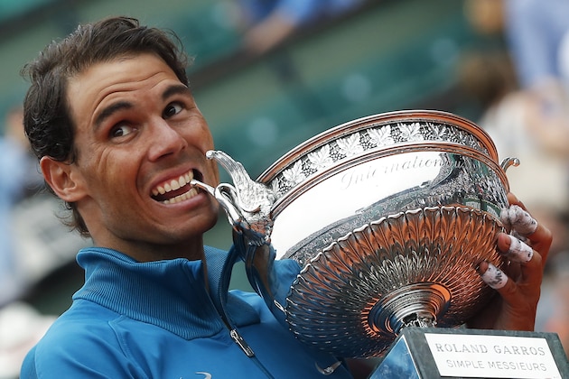 Eleven-times French Open winner Spain's Rafael Nadal bites the trophy as he celebrates after the men's final match of the French Open tennis tournament against Austria's Dominic Thiem who was beaten in three sets 6-4, 6-3, 6-2, at the Roland Garros stadium in Paris, France, Sunday, June 10, 2018. (AP Photo/Michel Euler)