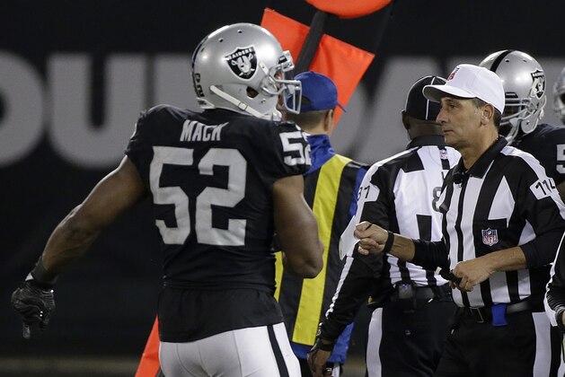 Referee Gene Steratore (114) carries a folded piece of paper used to determine a measurement next to Oakland Raiders defensive end Khalil Mack (52) during the second half of an NFL football game between the Raiders and the Dallas Cowboys in Oakland, Calif., Sunday, Dec. 17, 2017. The Cowboys won 20-17. (AP Photo/Eric Risberg)
