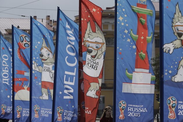 A woman walks past near the banners for the 2018 soccer World Cup in St. Petersburg, Russia, Tuesday, June 12, 2018. (AP Photo/Lee Jin-man)