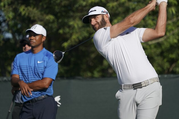 Dustin Johnson hits off the fourth tee as Tiger Woods looks on during a practice round for the U.S. Open Golf Championship, Tuesday, June 12, 2018, in Southampton, N.Y. (AP Photo/Carolyn Kaster)