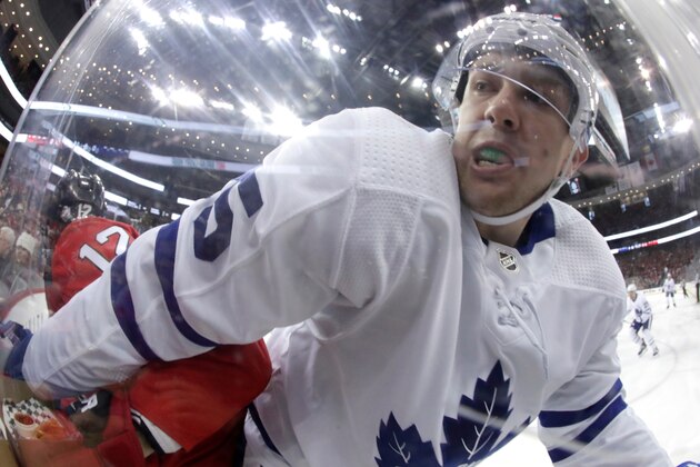 New Jersey Devils defenseman Ben Lovejoy (12) and Toronto Maple Leafs left wing James van Riemsdyk (25) compete for the puck near the boards during the first period of an NHL hockey game, Thursday, April 5, 2018, in Newark, N.J. (AP Photo/Julio Cortez)