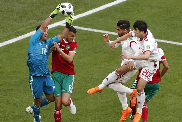 Morocco goalkeeper Monir El Kajoui, left, saves a ball during the group B match between Morocco and Iran at the 2018 soccer World Cup in the St. Petersburg Stadium in St. Petersburg, Russia, Friday, June 15, 2018. (AP Photo/Darko Vojinovic)