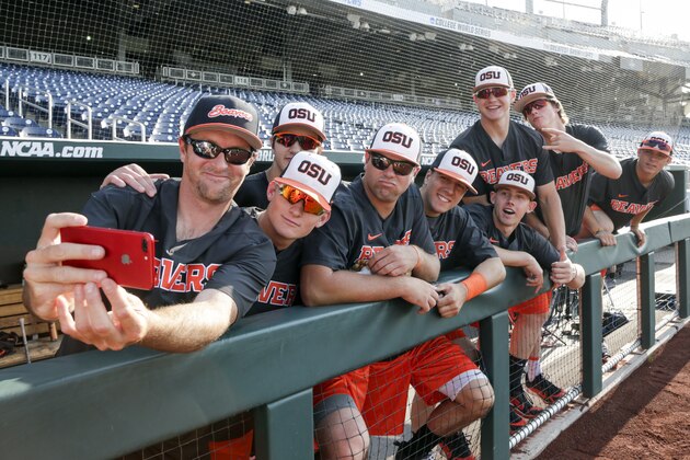 Oregon State undergraduate assistant coach Bill Rowe, left, takes a photo with team members before practice at TD Ameritrade Park in Omaha, Neb., Friday, June 15, 2018. Oregon State plays North Carolina on Saturday in the NCAA College World Series baseball tournament.. (AP Photo/Nati Harnik)