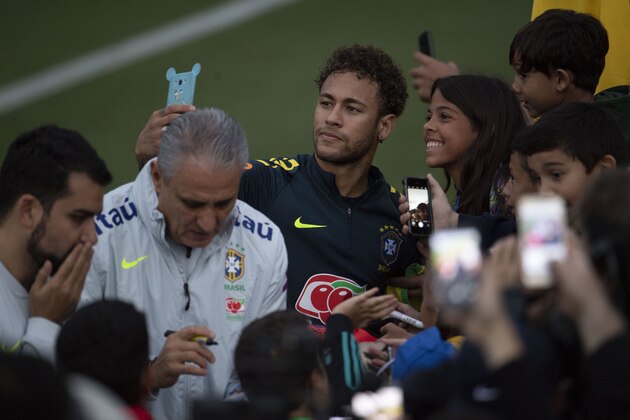 Brazil's Neymar (C) poses for a selfie with a fan as coach Tite (2-L) signs autographs to supporters after a training session of the national football team ahead of the FIFA 2018 World Cup, at Granja Comary training centre in Teresopolis, Rio de Janeiro, Brazil, on May 25, 2018. (Photo by Mauro PIMENTEL / AFP)        (Photo credit should read MAURO PIMENTEL/AFP/Getty Images)