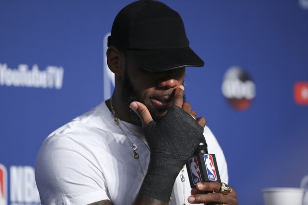 Cleveland Cavaliers forward LeBron James  wipes his face during a news conference following Game 4 of basketball's NBA Finals against the Golden State Warriors, early Saturday, June 9, 2018, in Cleveland. The Warriors defeated the Cavaliers 108-85 to win the NBA championship. (AP Photo/Carlos Osorio)