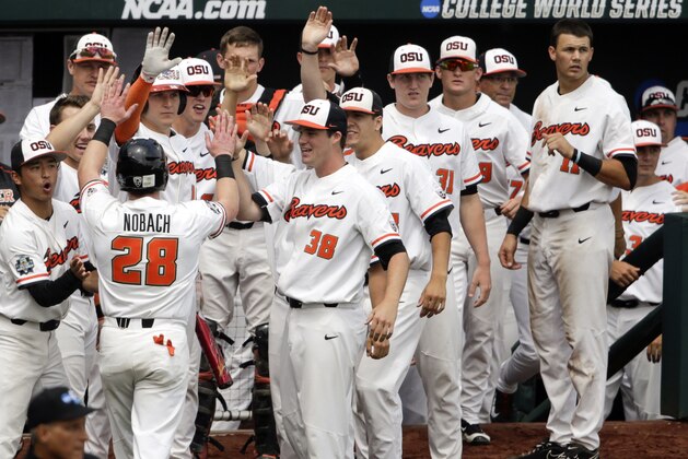 Oregon State's Kyle Nobach (28) is greeted at the dugout after he scored against Mississippi State on a one-run single by Michael Gretler in the second inning of an NCAA College World Series baseball game in Omaha, Neb., Friday, June 22, 2018. (AP Photo/Nati Harnik)