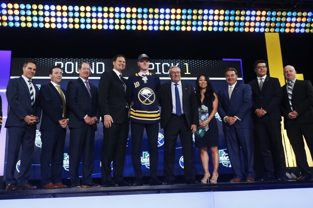 Rasmus Dahlin, center, of Sweden, stands on stage after being selected by the Buffalo Sabres during the NHL hockey draft in Dallas, Friday, June 22, 2018. (AP Photo/Michael Ainsworth)