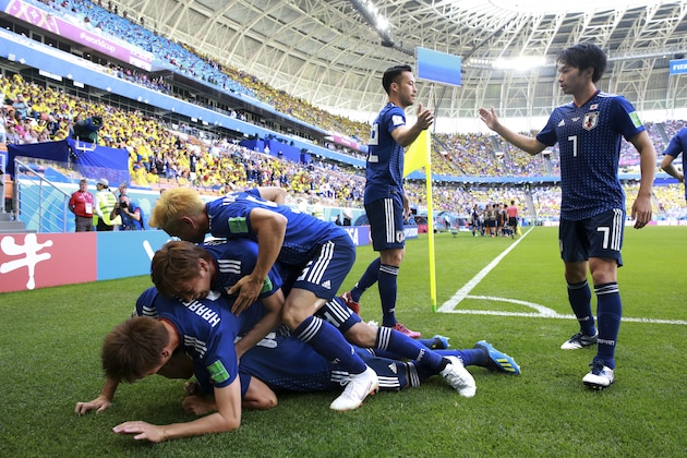 Teammates crowd over Japan's Shinji Kagawa after he scored from the penalty spot his side's first goal against Colombia during a group H match at the 2018 soccer World Cup in the Mordavia Arena in Saransk, Russia, Tuesday, June 19, 2018. (AP Photo/Eugene Hoshiko)