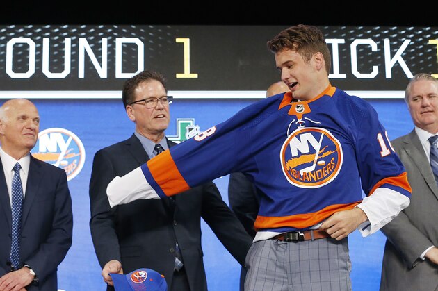 Oliver Wahlstrom puts on a New York Islanders jersey after being selected by the team during the NHL hockey draft in Dallas, Friday, June 22, 2018. (AP Photo/Michael Ainsworth)
