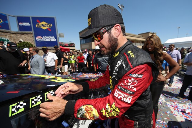 SONOMA, CA - JUNE 24:  Martin Truex Jr., driver of the #78 5-hour ENERGY/Bass Pro Shops Toyota, celebrates in victory lane by placing the winner's sticker on his car after winning the Monster Energy NASCAR Cup Series Toyota/Save Mart 350 at Sonoma Raceway on June 24, 2018 in Sonoma, California.  (Photo by Chris Graythen/Getty Images)