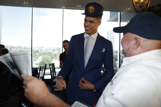 Steve Stretz, right, shows the front page of the sports section of The Denver Post to Michael Porter Jr., center, the Denver Nuggets first-round pick in the NBA Draft, after a news conference to introduce the player to the media Friday, June 22, 2018, in Denver. (AP Photo/David Zalubowski)
