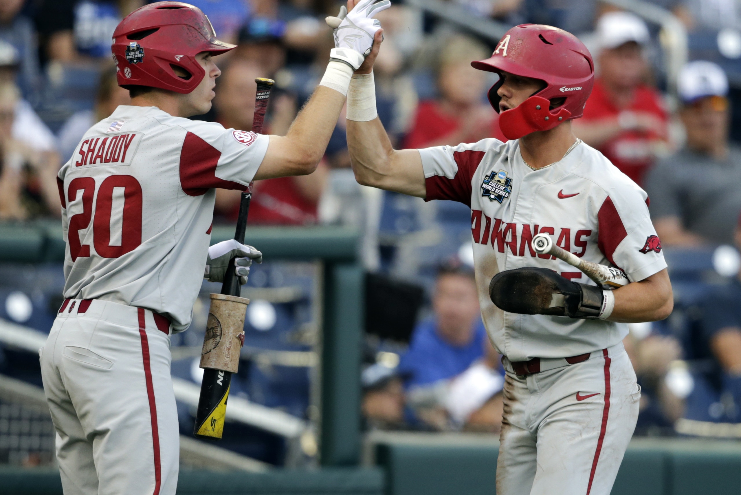 Arkansas' Casey Martin, right, high-fives teammate Carson Shaddy (20) after scoring against Florida on an RBI-single in the first inning of an NCAA College World Series baseball game in Omaha, Neb., Friday, June 22, 2018. (AP Photo/Nati Harnik)