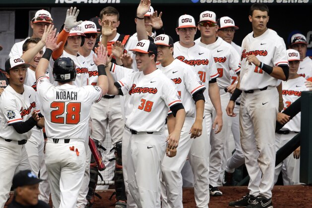 Oregon State's Kyle Nobach (28) is greeted at the dugout after he scored against Mississippi State on a one-run single by Michael Gretler in the second inning of an NCAA College World Series baseball game in Omaha, Neb., Friday, June 22, 2018. (AP Photo/Nati Harnik)