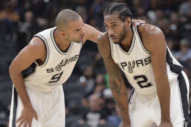 San Antonio Spurs guard Tony Parker (9), of France, talks with forward Kawhi Leonard during the second half of the team's preseason NBA basketball game against the Houston Rockets, Friday, Oct. 21, 2016, in San Antonio. (AP Photo/Darren Abate)