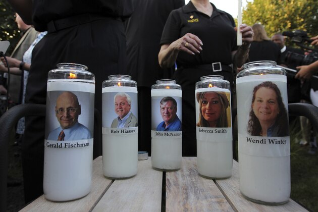 Photos of five journalists adorn candles during a vigil across the street from where they  were slain in their newsroom in Annapolis, Md., Friday, June 29, 2018. Prosecutors say Jarrod W. Ramos opened fire Thursday in the Capital Gazette newsroom. (AP Photo/Jose Luis Magana)