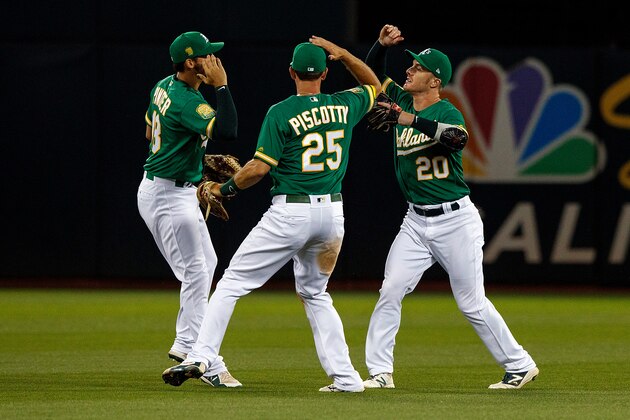 OAKLAND, CA - JUNE 29:  Chad Pinder #18 of the Oakland Athletics, Stephen Piscotty #25 and Mark Canha #20 celebrate after the game against the Cleveland Indians at the Oakland Coliseum on June 29, 2018 in Oakland, California. The Oakland Athletics defeated the Cleveland Indians 3-1. (Photo by Jason O. Watson/Getty Images)