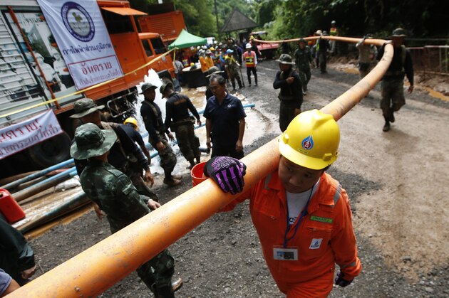 Rescuer carrying water pipe makes their way up at the entrance to a cave complex where 12 boys and their soccer coach were trapped inside when heavy rains flooded the cave, in Mae Sai, Chiang Rai province, in northern Thailand, Wednesday, July 4, 2018. The Thai soccer teammates stranded more than a week in a partly flooded cave said they were healthy on a video released Wednesday, as heavy rains forecast for later this week could complicate plans to safely extract them. (AP Photo/Sakchai Lalit)