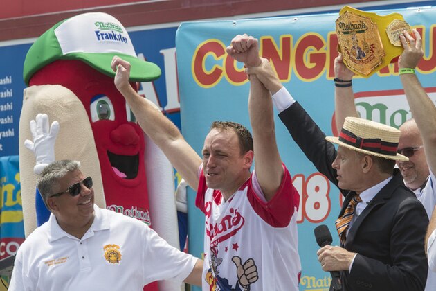 Reigning champion Joey Chestnut, center, celebrates with Master of ceremonies  George Shea, right, and Brooklyn District Attorney Eric Gonzalez, after winning the men's competition of the Nathan's Famous Fourth of July hot dog eating contest in the final seconds of the competition, Wednesday, July 4, 2018, in New York's Coney Island.  Chestnut broke his own world record by eating 74 hot dogs in 10 minutes. (AP Photo/Mary Altaffer)