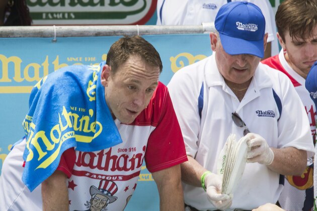 A judge counts the plates of hot dogs Joey Chestnut, left, at the end of the men's competition of the Nathan's Famous Fourth of July hot dog eating contest in the final seconds of the competition, Wednesday, July 4, 2018, in New York's Coney Island.  Chestnut broke his own world record by eating 74 hot dogs in 10 minutes. (AP Photo/Mary Altaffer)