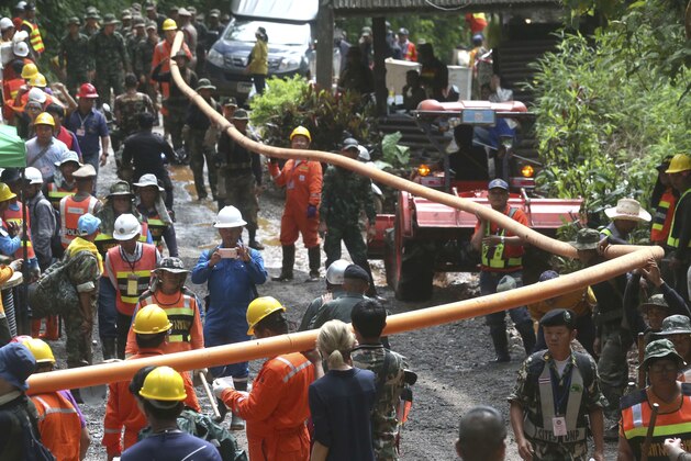 Rescuer carry water pipe makes their way up at the entrance to a cave complex where 12 boys and their soccer coach were trapped inside when heavy rains flooded the cave, in Mae Sai, Chiang Rai province, in northern Thailand, Wednesday, July 4, 2018. The Thai soccer teammates stranded more than a week in a partly flooded cave said they were healthy on a video released Wednesday, as heavy rains forecast for later this week could complicate plans to safely extract them. (AP Photo/Sakchai Lalit)