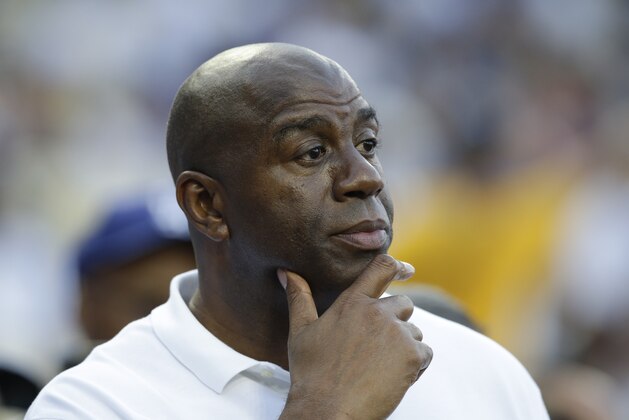 FILE - In this May 27, 2014, file photo, Magic Johnson watches before a baseball game between the Los Angeles Dodgers and Cincinnati Reds in Los Angeles. Magic Johnson says he's pleased pro athletes are supporting peaceful protests around the nation by using