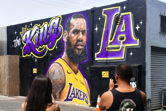People photograph a mural of LeBron James in a Los Angeles Lakers jersey in Venice, California on July 9, 2018. - It was originally revealed July 6, 2018, and then vandalized over the weekend, and re-touched up again with the word 'of' not repainted from the original words 'the King of LA'. Artists Jonas Never and Menso One painted the mural to welcome LeBron James to Los Angeles, outside the Baby Blues BBQ resturant in Venice, California. (Photo by Frederic J. BROWN / AFP) / RESTRICTED TO EDITORIAL USE - MANDATORY MENTION OF THE ARTIST UPON PUBLICATION - TO ILLUSTRATE THE EVENT AS SPECIFIED IN THE CAPTION        (Photo credit should read FREDERIC J. BROWN/AFP/Getty Images)