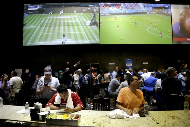 Men sit at a bar while researching bets at the Meadowlands Racetrack, Saturday, July 14, 2018, in East Rutherford, N.J. Meadowlands Racetrack started taking sports betting on Saturday, becoming the fourth sports betting outlet in New Jersey following the state's U.S. Supreme Court victory in a case that cleared the way for all 50 states to legalize sports betting. (AP Photo/Julio Cortez)