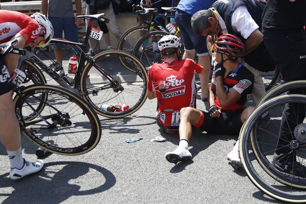 Australia's Richie Porte, right, receives medical attention as he sits on the road with Belgium's Jens Keukeleire, center, after crashing during the ninth stage of the Tour de France cycling race over 156.5 kilometers (97.2 miles) with start in Arras and finish in Roubaix, France, Sunday, July 15, 2018. Porte quit the race after the crash. (AP Photo/Christophe Ena )