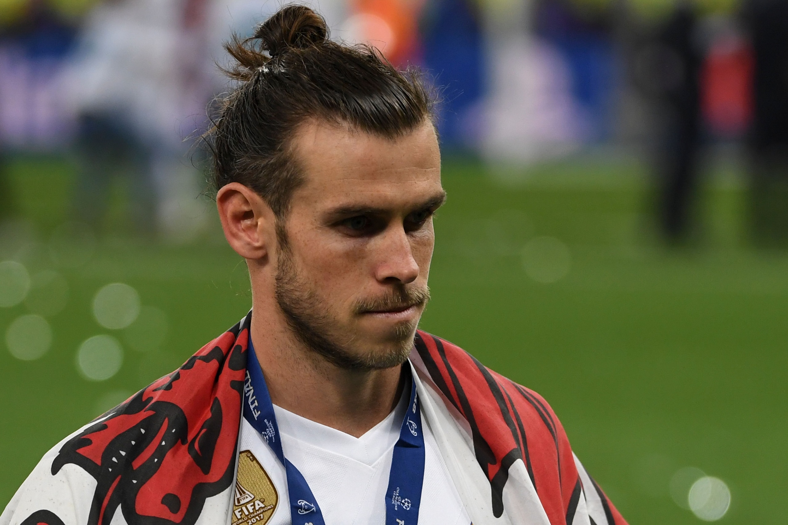 Real Madrid's Welsh forward Gareth Bale with his winner's medal and a Welsh flag on the pitch as Real Madrid players celebrate winning the UEFA Champions League final football match between Liverpool and Real Madrid at the Olympic Stadium in Kiev, Ukraine on May 26, 2018. - Real Madrid defeated Liverpool 3-1. (Photo by Paul ELLIS / AFP)        (Photo credit should read PAUL ELLIS/AFP/Getty Images)