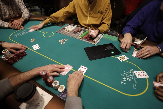 In this Wednesday, Feb. 3, 2016 photo a card dealer deals a game of poker to patrons at Twin River Casino, in Lincoln, R.I. Casinos far from Las Vegas are experimenting with different ways to draw millennials. Twin River Casino removed 274 slot machines to make way in December for more poker and other table games favored by younger gamblers. (AP Photo/Steven Senne)