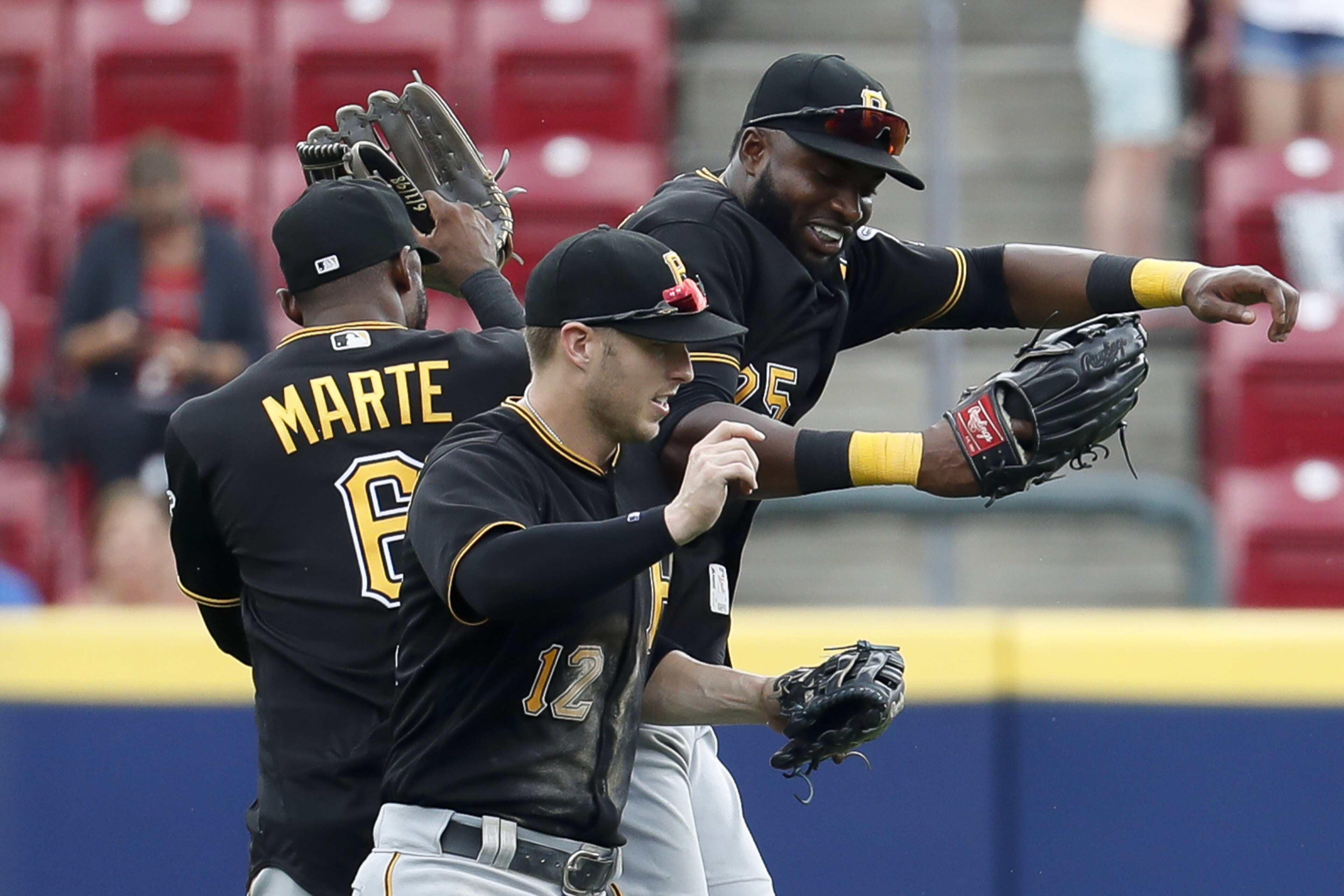 Pittsburgh Pirates center fielder Starling Marte (6), left fielder Corey Dickerson (12), and right fielder Gregory Polanco, right, celebrate after closing the ninth inning of a baseball game against the Cincinnati Reds, Sunday, July 22, 2018, in Cincinnati. (AP Photo/John Minchillo)