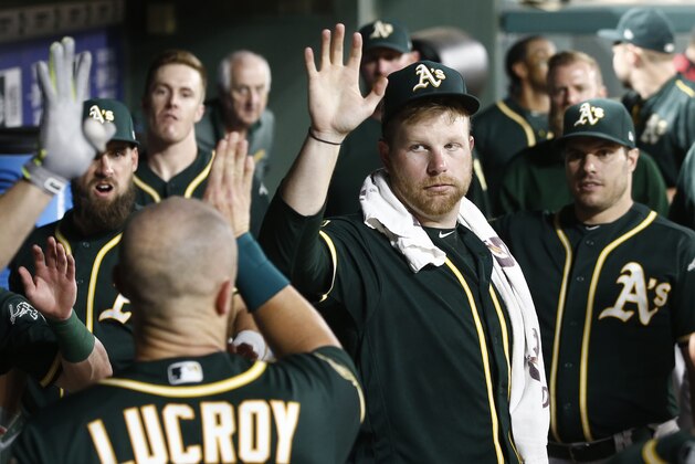 Oakland Athletics starting pitcher Brett Anderson, center, congratulates Jonathan Lucroy after he scored against the Texas Rangers during the seventh inning of a baseball game Monday, July 23, 2018, in Arlington, Texas. (AP Photo/Mike Stone)
